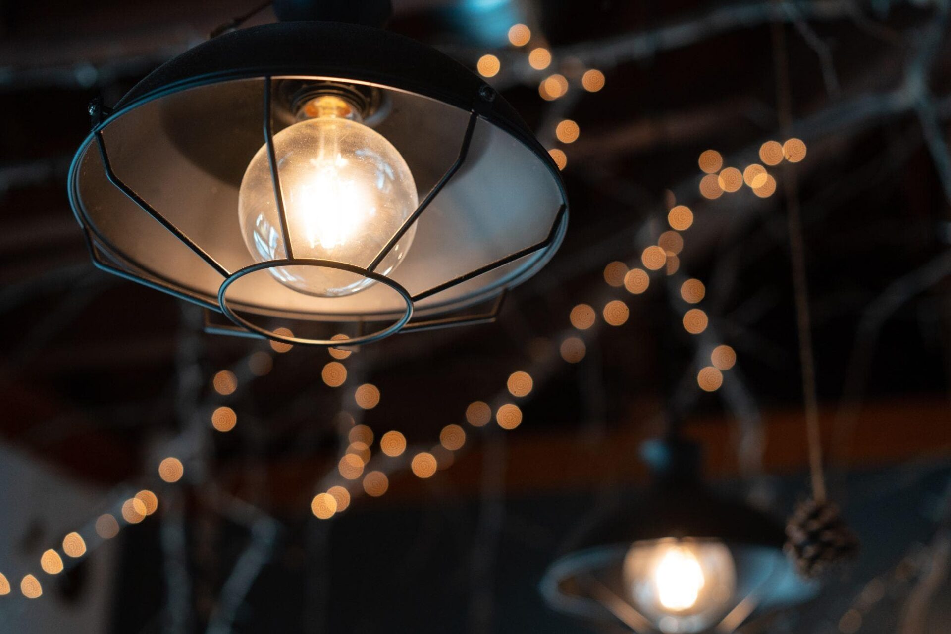 A round, black, decorative lamp hanging outside on a dark background